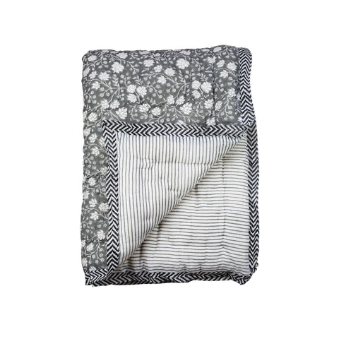 A folded quilt with a floral pattern on one side and a striped pattern on the other, with a chevron border.