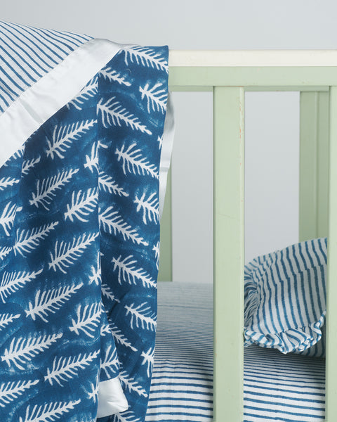 reversible indigo muslin cot blanket with white satin trim printed with stripes and feathers