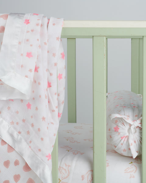 reversible pink muslin cot blanket with white satin trim and pink hearts and stars block print designs