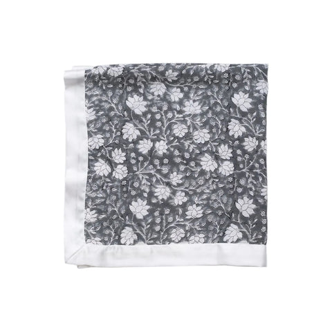A white cotton muslin cloth with a charcoal grey floral pattern, folded neatly.