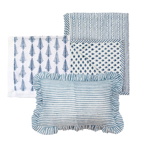 A cotton baby blanket, muslin square and mini ruffle pillow with block printed designs on a white background