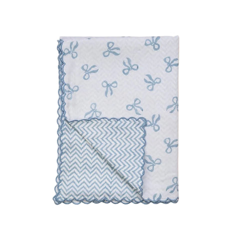 Reversible cotton baby blanket with scalloped edge and blue bow pattern on a white background